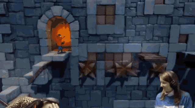 a man and a woman are playing a video game with a brick wall in the background