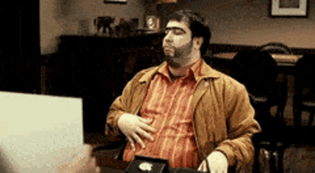 a man with a beard is sitting at a table with an apple laptop on it