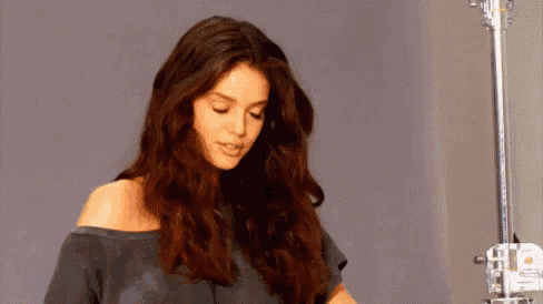 a woman with long dark hair is standing in front of a microphone .