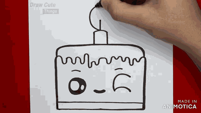 a person is drawing a cake with a face on a piece of paper that says draw cute things on it