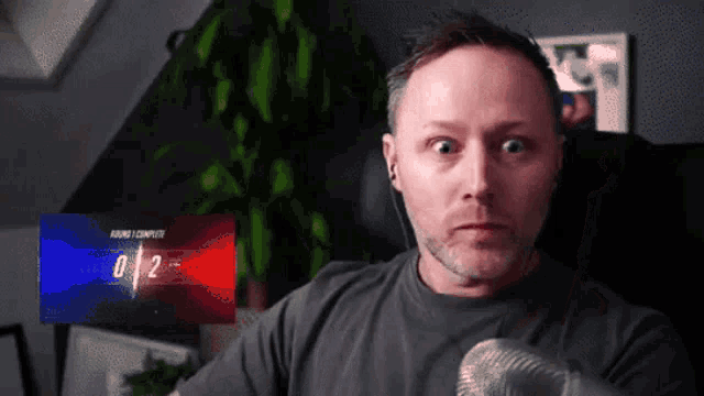a man with a microphone in front of a screen that says 0/2