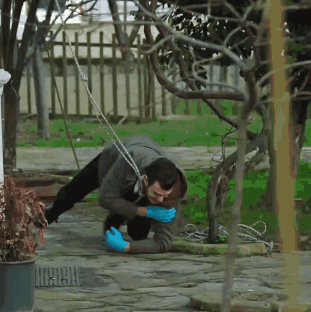 a man wearing blue gloves crawls on the ground