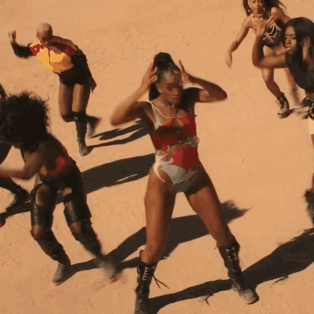 a woman in a red and blue swimsuit is dancing in the sand