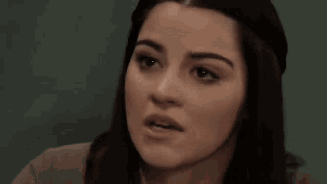 a close up of a woman 's face with her hands folded
