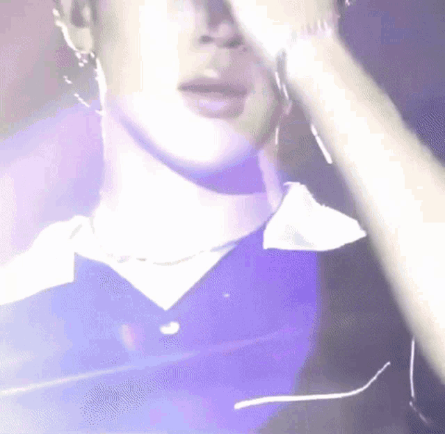 a close up of a person 's face with a purple light shining on it .