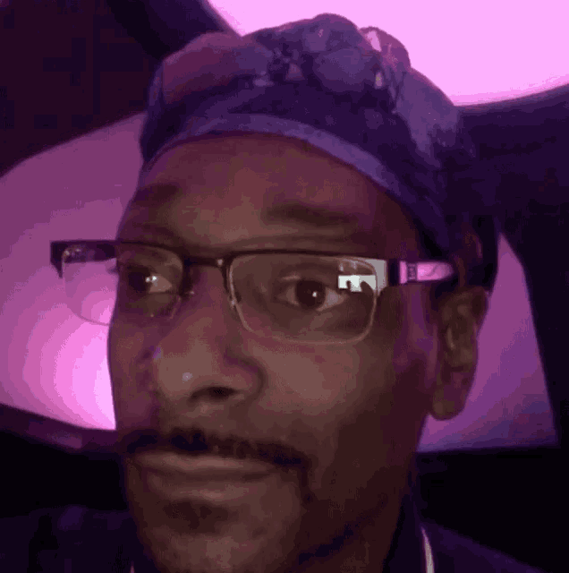 a man wearing glasses and a blue hat is smiling