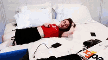 a woman in a red top is laying on a bed next to a fedex box