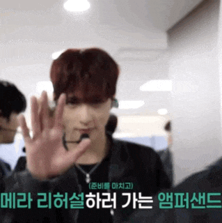 a man with red hair is waving his hand in front of a sign that says ' korean '