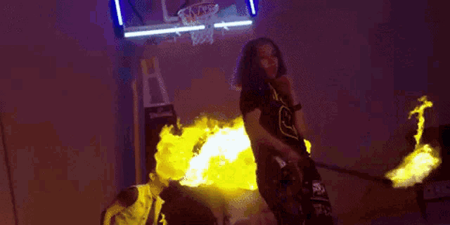 a man in a nirvana shirt is standing in front of a basketball hoop with fire coming out of it