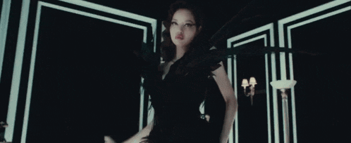a woman in a black dress and gloves is holding a microphone in her hand .