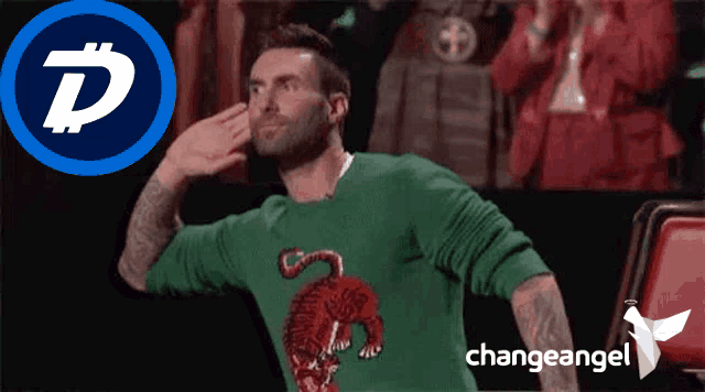 a man wearing a green sweater with a tiger on it salutes in front of a change angel logo