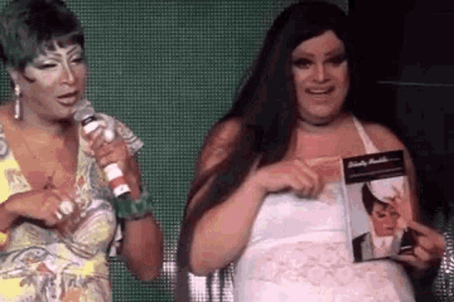 two women are standing next to each other on a stage holding a microphone .