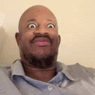 a bald man with a beard is making a funny face while wearing a blue shirt .