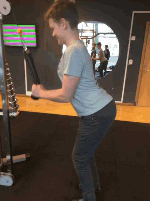 a man in a grey shirt is lifting a rope