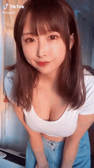 a woman in a white crop top and blue jeans is standing in a room .