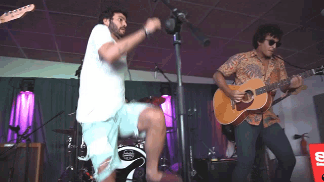 a man playing a guitar and another man playing a drum set