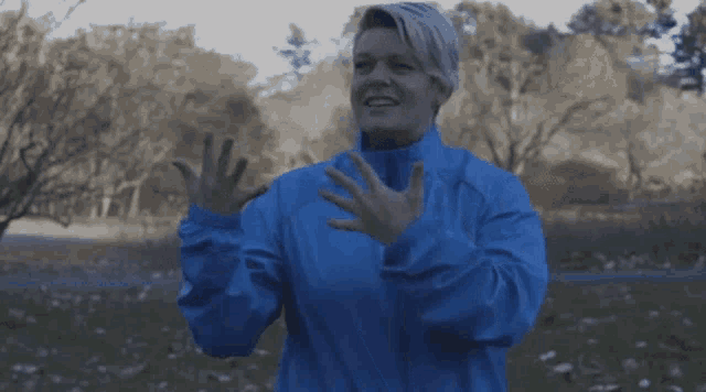 a woman in a blue jacket holds her hands up