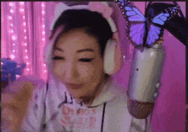 a woman wearing headphones and a butterfly on her ear is standing in front of a microphone .