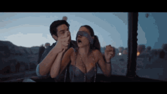 a man is holding a blindfolded woman 's hand in a hot air balloon