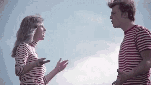 a man and a woman in striped shirts are standing next to each other and talking .