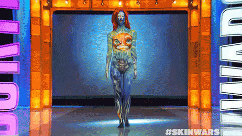 a woman with her body painted is walking down a runway