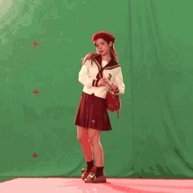 a girl in a red skirt is dancing in front of a green screen