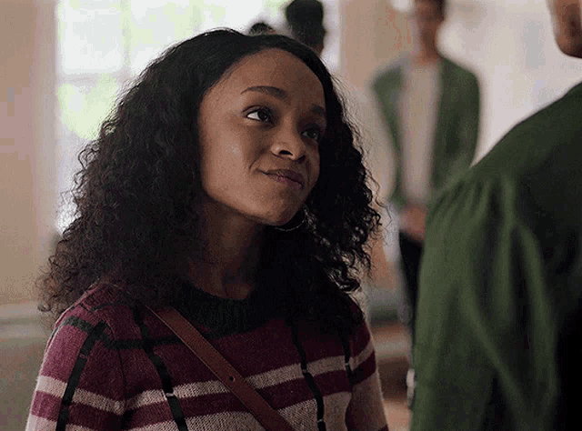 a woman with curly hair is wearing a striped sweater and earrings