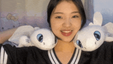 a girl holding two stuffed animals on her shoulders