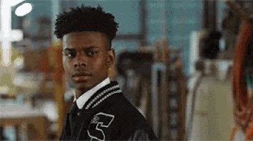 a young man wearing a varsity jacket with the letter r on it