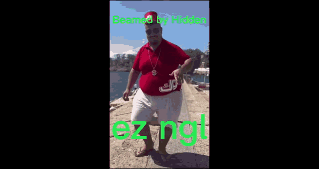 a fat man in a red shirt and white shorts is standing on a pier .