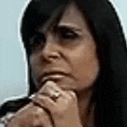 a woman with long black hair is thinking with her hand on her chin .