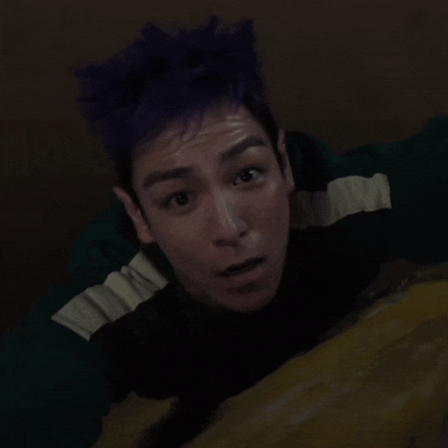 a man with purple hair is wearing a green sweater with nasa on the sleeve