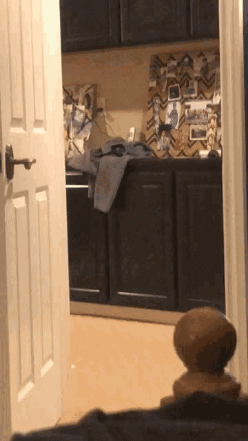 a door is open to a laundry room with black cabinets and pictures on the wall