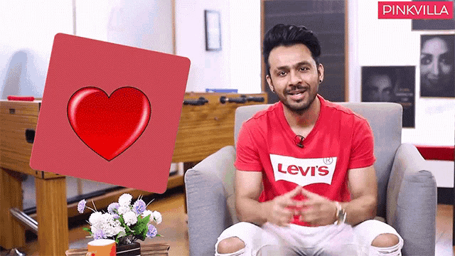 a man wearing a red levi 's shirt sitting in a chair