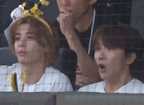 a couple of people are sitting in a stadium watching a baseball game .