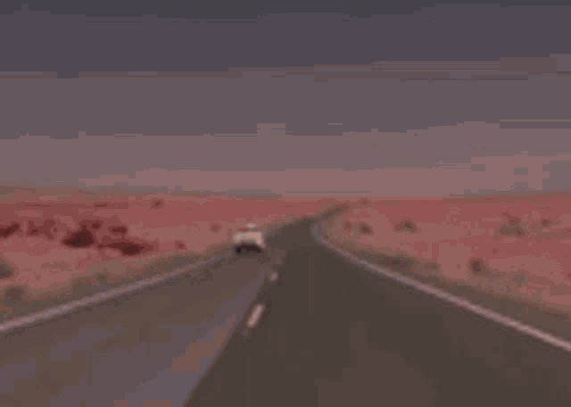 a car is driving down a desert highway .