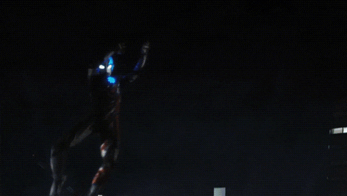 two monsters are fighting in a city at night with a few buildings lit up