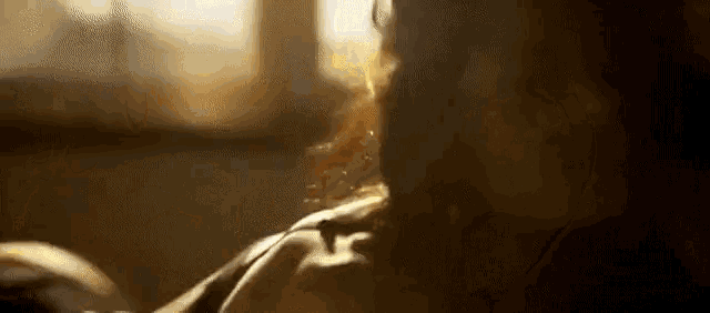 a close up of a woman 's face in a dark room with a window in the background .