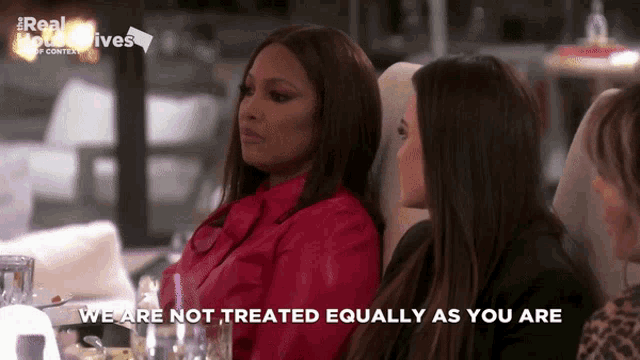 two women are sitting at a table with the words we are not treated equally as you are