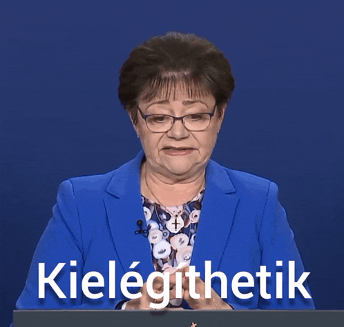 a woman wearing glasses and a blue jacket stands in front of a podium that says kielegithetik on it
