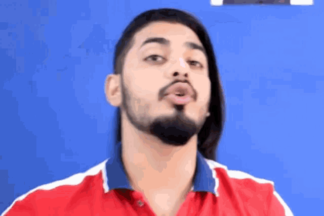a man with long hair and a beard is making a funny face with his tongue out .