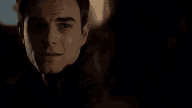 a close up of a man 's face in the dark with a woman behind him .