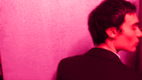 a man standing in front of a pink wall