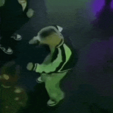 a person in a green and black striped jacket is dancing on a stage .