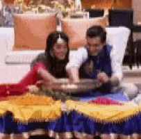 a man and a woman are sitting at a table with a bowl of food on it .