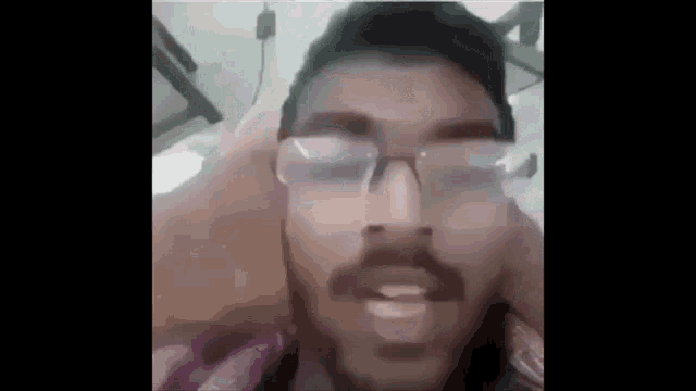 a man with a beard and glasses is talking on a video call .