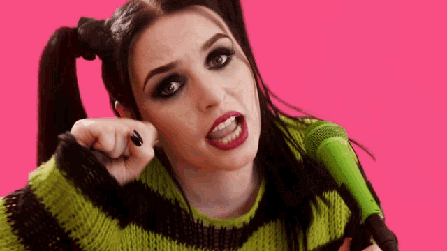 a woman in a green and black striped sweater is holding a green microphone