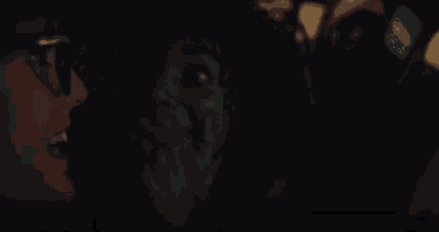 a group of people are sitting in a dark room and one of them is wearing glasses
