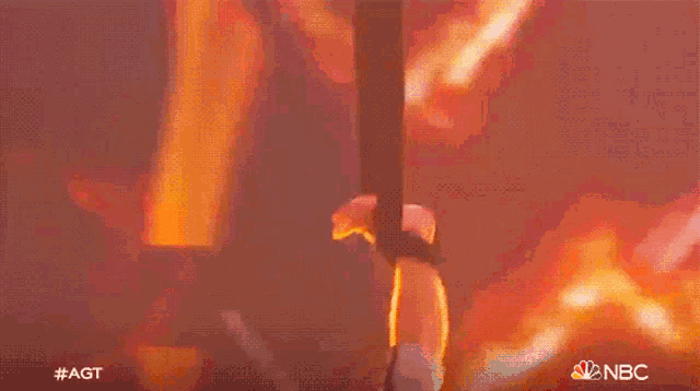 a person is hanging from a rope in front of a red background with nbc written on it