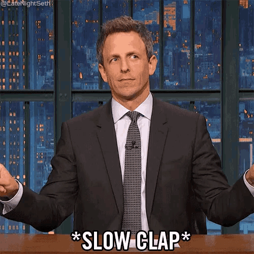 a man in a suit and tie is clapping his hands and saying slow clap